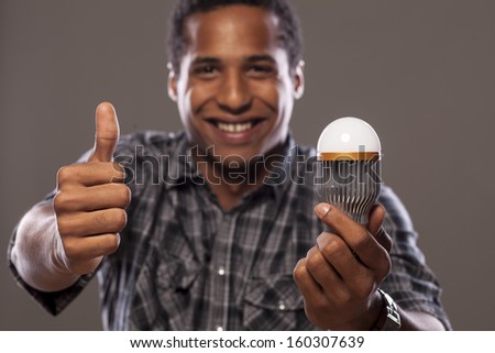 smiling young African American men holding a LED bulb and showing thumbs up