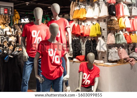 Mannequins dressed in red t-shirts with percentage signin the shopping mall. Season of discounts and sales. Black Friday