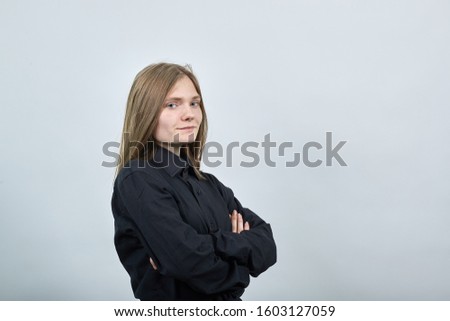 Disappointed young woman in fashion black shirt isolated on gray background in studio keeping hands crossed, looking at camera. People sincere emotions, lifestyle concept.