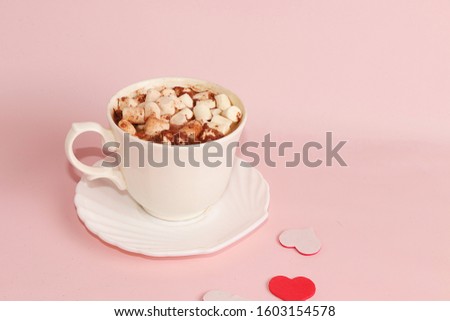 Cup of cocoa with marshmallows and hearts on a pink background. Wishes good morning and have a nice day, the atmosphere of winter holidays