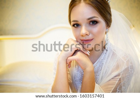 The bride in a white coat on the bed in a wedding morning