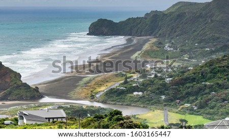 Aerial view of North Piha beach with sand dunes and Piha village houses