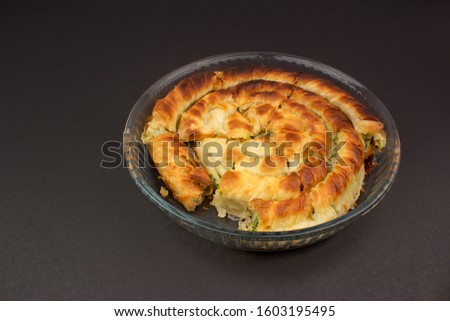Pastry pie in Pyrex. wrap pies pastry. spinach pie. Isolated shot on black ground. Shooting with horizontal perspective.