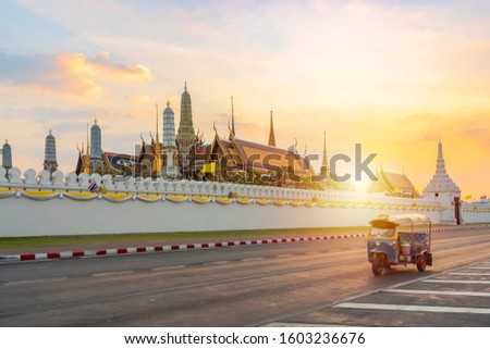 Grand palace and Wat phra keaw at sunset bangkok, Thailand. Blue Tuk Tuk, Thai traditional taxi is the front scene.