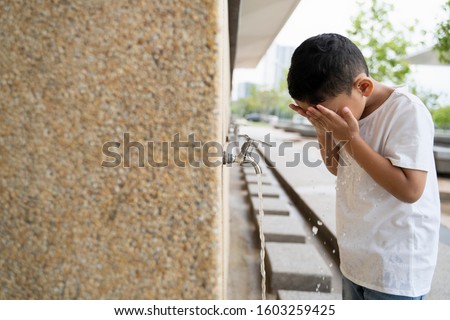 Muslim Kid takes ablution before prayer Royalty-Free Stock Photo #1603259425