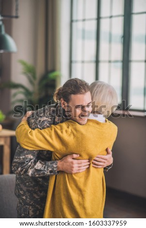 Happy meeting. Young happy man in camouflage meeting his mom