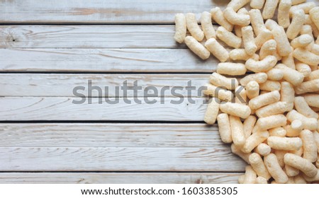 Lots of yellow corn sticks on a white wooden background. Delicious airy dessert. Concept and picture, copy space. Baby food.