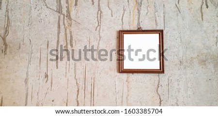 Small empty brown picture frame mock up on grey or gray grunge wall with copy space and area for adding or filling text. 