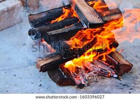 Wood burning in a fire which will eventually turn into coals which will be used to braai (cook) meat. 