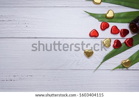 valentine day concept. mini hearts red and gold color with green tree leafs. white wood texture background. anniversary, mother's day and birthday greeting, copyspace, topview