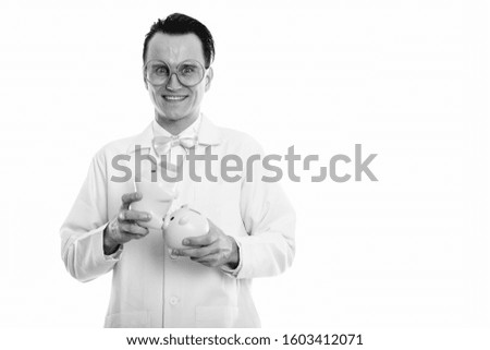 Studio shot of happy crazy man doctor smiling while holding two piggy banks on top of each other