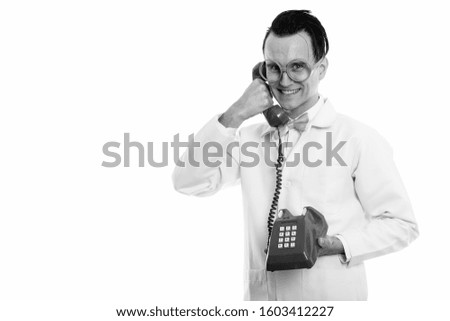 Studio shot of happy crazy man doctor smiling while talking on old telephone