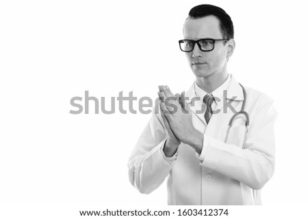 Studio shot of young handsome man doctor with hands together