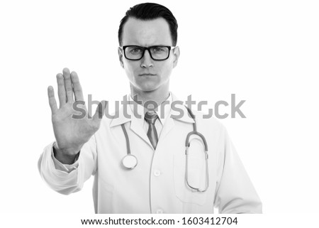 Studio shot of young handsome man doctor with stop hand gesture