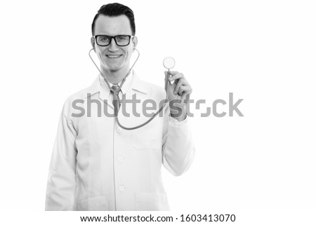 Studio shot of young happy man doctor smiling while using stethoscope