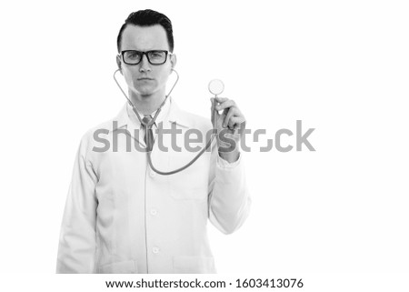 Studio shot of young handsome man doctor using stethoscope