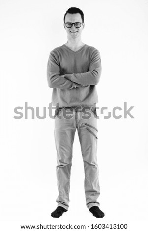 Full body shot of young happy man smiling and wearing eyeglasses with arms crossed