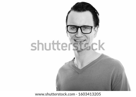 Studio shot of young happy man smiling while wearing eyeglasses