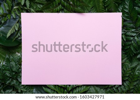 Tropical layout made of palm leaves with copy space and pink greeting card for text background. Flat lay. Green palm leaf backdrop