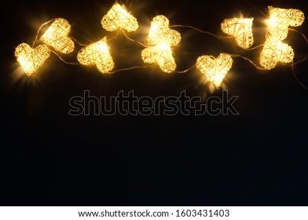 Beautiful heart-shaped fairy lights glowing on dark. St. Valentine's Day background
