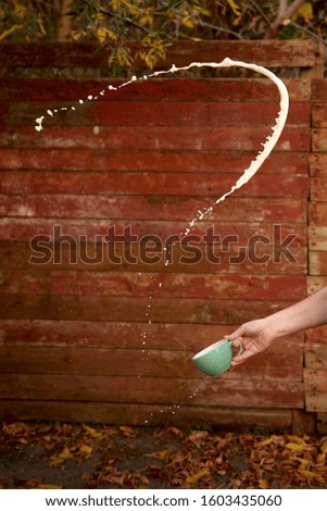 
cup with milk spray up on wooden wall background