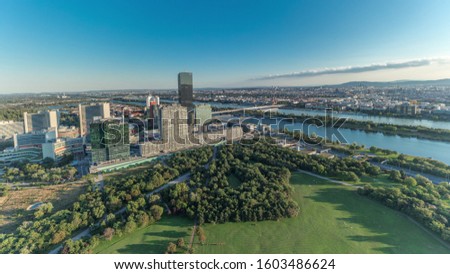 Aerial panoramic view of Vienna city with Donau City skyscrapers, historic buildings and a riverside promenade timelapse in Austria. Evening skyline before sunset from Danube Tower viewpoint