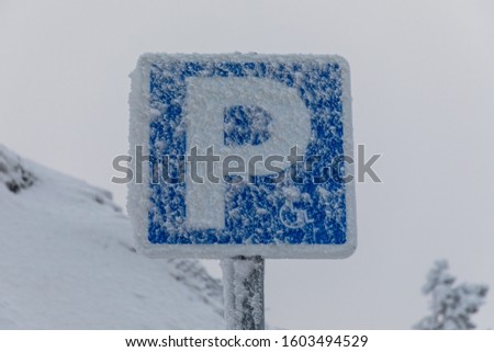Parking sign for disabled people covered with ice and snow