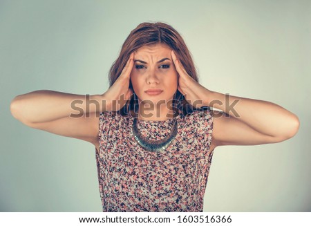 Woman looking at you camera hands on head having headache or stress. Mixed race model isolated on light green background with copy space. Horizontal image.