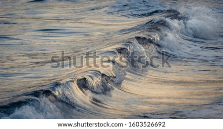 Background. Wave breaking diagonally in the light of the sunset. High shutter speed