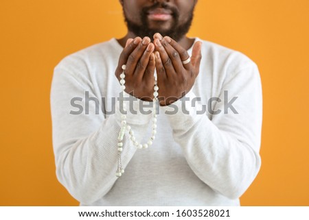 African-American Muslim man praying against color background