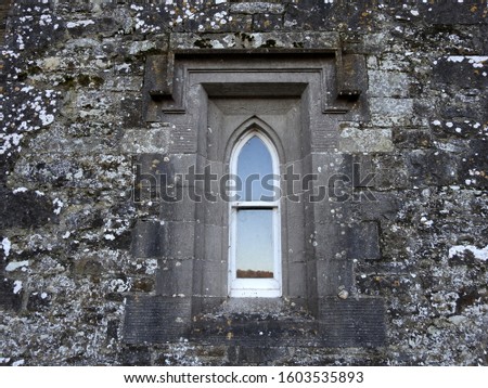 Old bullet shaped castle 
window coming out of a brick wall.