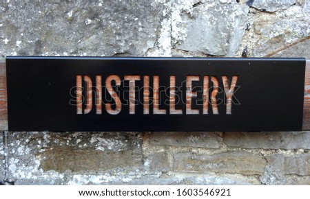 Distillery sign cut out from wood on brick wall. 