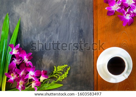 Coffee cup is on wooden floor background near dark rock floor backgrounds with orchids ,flowers. 