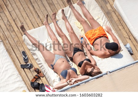 A man and two women are sunbathing in the sun..