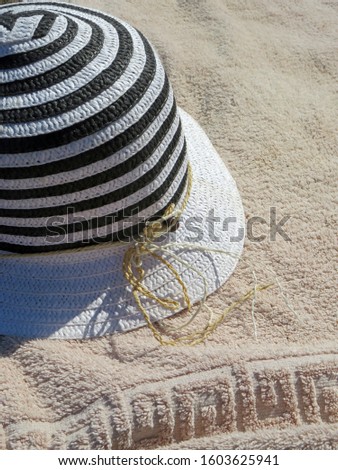 Striped wicker hat on a towel on a Sunny beach on a summer day