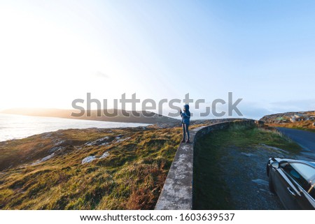 woman standing  at view point and making photo of sea landscape