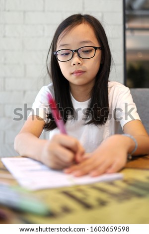 Little Asian girl doing homework at home