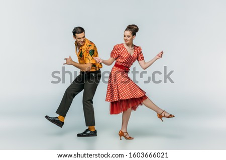 young dancers holding hands while dancing boogie-woogie on grey background Royalty-Free Stock Photo #1603666021