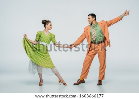 stylish dancers holding hands and looking at each other while dancing boogie-woogie on grey background Royalty-Free Stock Photo #1603666177