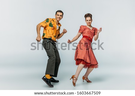 cheerful dancers looking at camera while dancing boogie-woogie on grey background Royalty-Free Stock Photo #1603667509