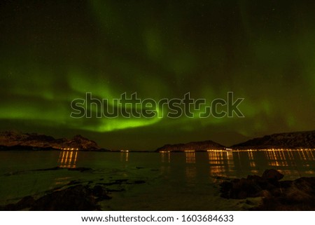 beautiful northern lights. Starry sky with polar lights and many clouds and stars on the sky winter landscape with aurora, sea with sky reflection and snowy mountains. long shutter speed.