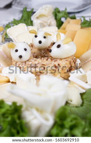 Holiday Christmas salad mouse 2020 New Year cheese piece shape on a white plate. Boiled eggs with cheese look like white mice (rats), horizontal, close up