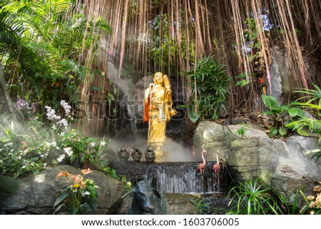 the golden buddha status stand under big tree