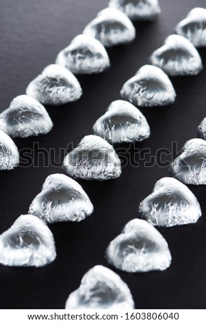 Selective focus of candies in heart shape on black background
