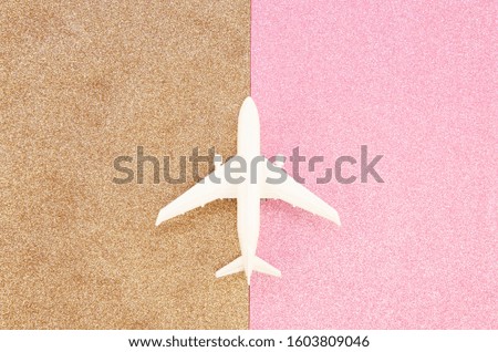 Fly tickets and holidays concept. Flat lay airplane on a rose gold and pink glitter paper background
