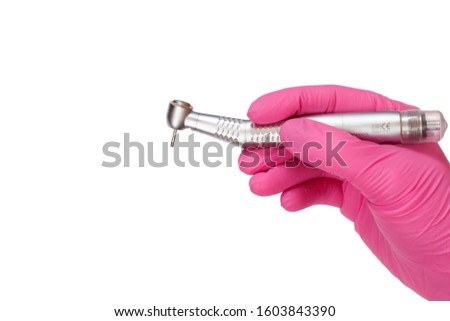 Dentist's hand in a latex glove with new high-speed dental handpiece on white isolated background. Medical tools concept. Royalty-Free Stock Photo #1603843390