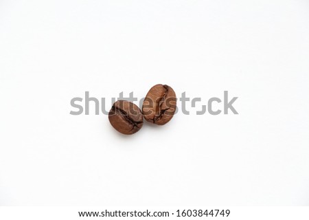 Close-up view of isolated couple of brown roasted coffee beans on the white background. Left coffee bean is arabica, right - robusta. Theme of drinks ingredients.