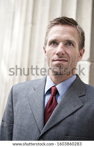 Portrait of a serious businessman standing outdoors in front of a row of classical fluted columns