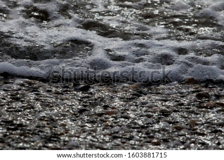 Small stones and foam in the surf line on the Black Sea in the city of Yevpatoriya (Crimea, Crimean peninsula).