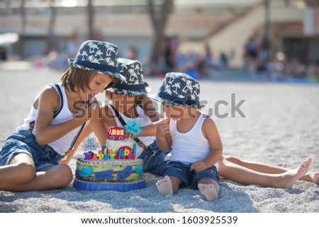 Sweet boys, celebrating on the beach birthday with car theme cake and decoration, summertime
